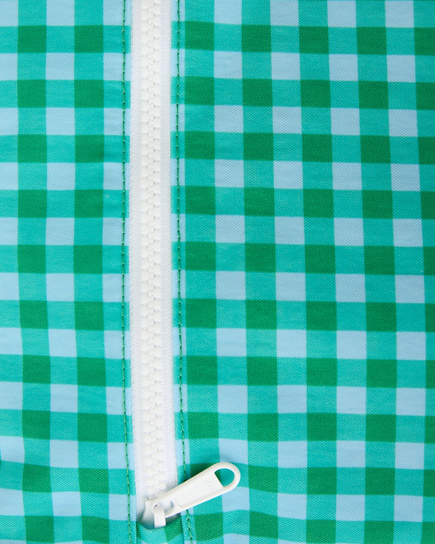 A close up of the zipper of the Wet/Dry Bag Set in Teal Gingham on a beige background.