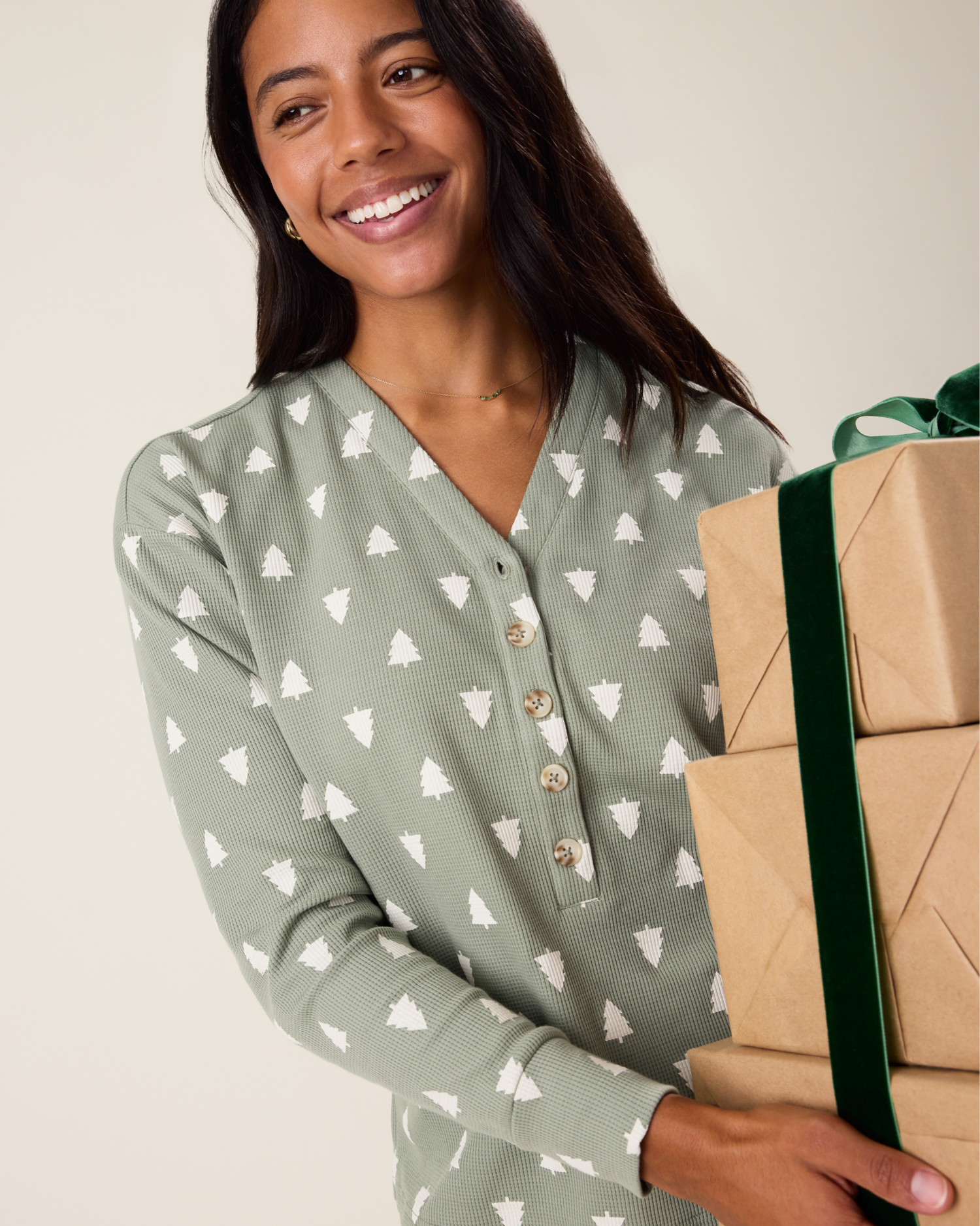 Woman wearing the top of the Waffle Maternity & Nursing Lounge Set in Sage Trees - sage green background with white tree pattern, holding wrapped gifts
