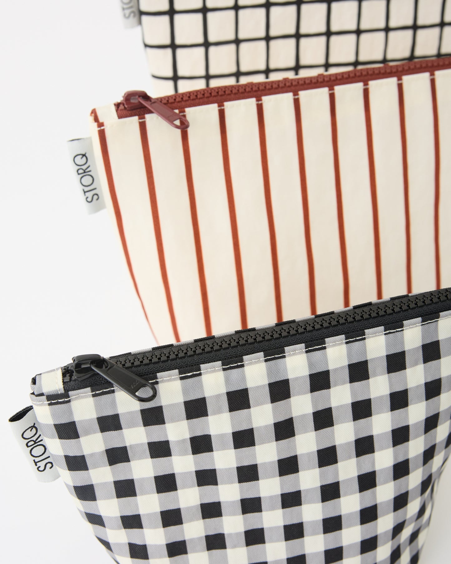 Zipper Pouch Three-Piece Set in Black Grid on a beige background.