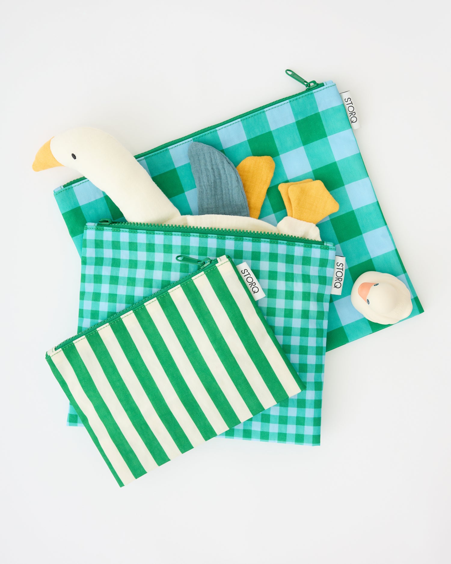 Zipper Pouch Three-Piece Set in Teal Gingham with a rubber ducky and a goose lovey sticking out of the medium sized pouch, on a beige background.