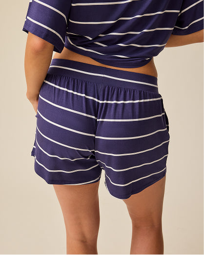 Back view of model wearing Aria Bamboo Casual Lounge Short in Navy & White Stripe on a beige background.