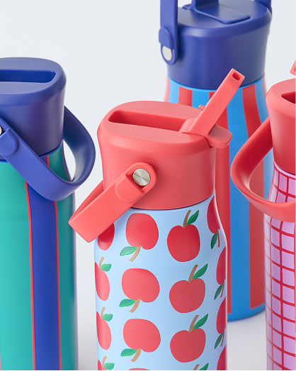 All four Cool Kid Water Bottles, in Orchid Grid, Blue Apple, Blue & Rust Stripe, and Navy & Green Stripe, on a beige background.