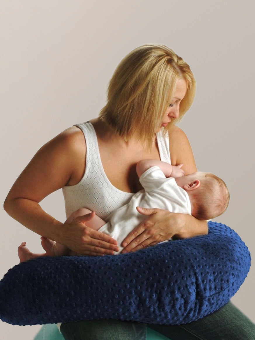 Model sitting and using the Luna Lullaby - Nursing Pillow in Navy Dot while nursing baby