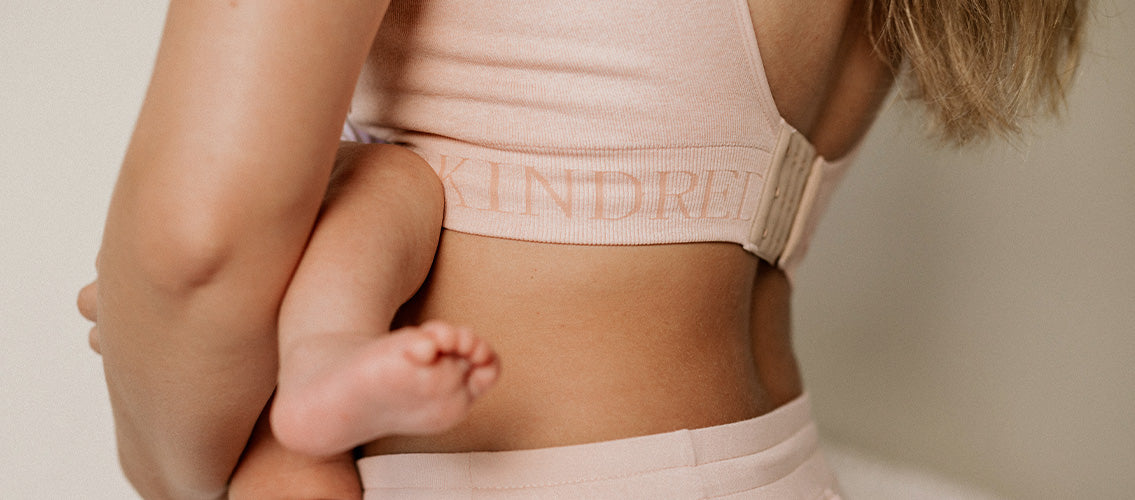 Cropped in image of model holding infant, showing Kindred Bravely bra band