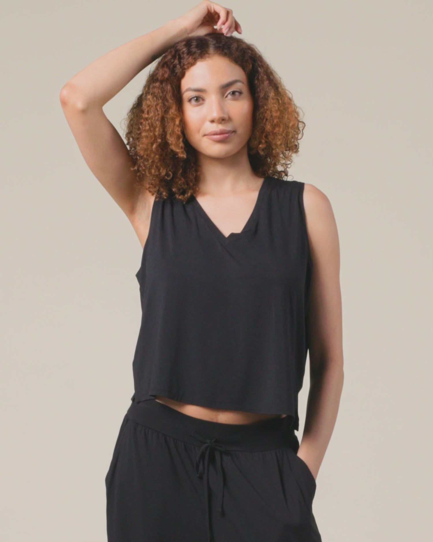 Video of model showing fit on Aria Bamboo Cropped V-neck Tank in Black and Aria Bamboo Casual Lounge Pant in Black on a beige background.