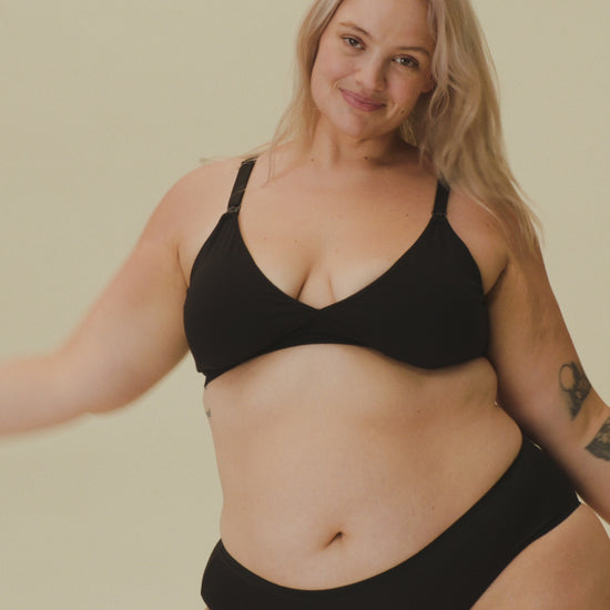 Video of Model showing the fit on SoftStretch Cotton Nursing Bra in Black and SoftStretch Cotton Maternity & Postpartum Hipster in Black on a beige background.