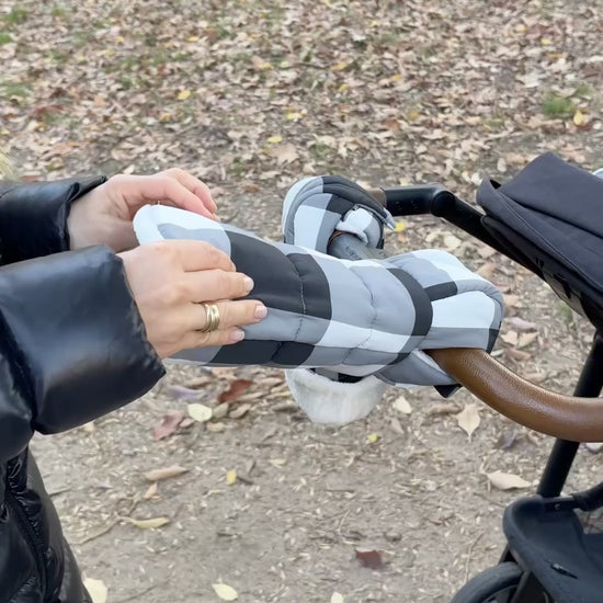Model prepares the Cozy Stroller Mitts in Buffalo Plaid for her winter stroller party in the park with baby. As she rolls them open, you can see the fuzzy soft interior just before she pops both hands in, ready to push the stroller in complete comfort.