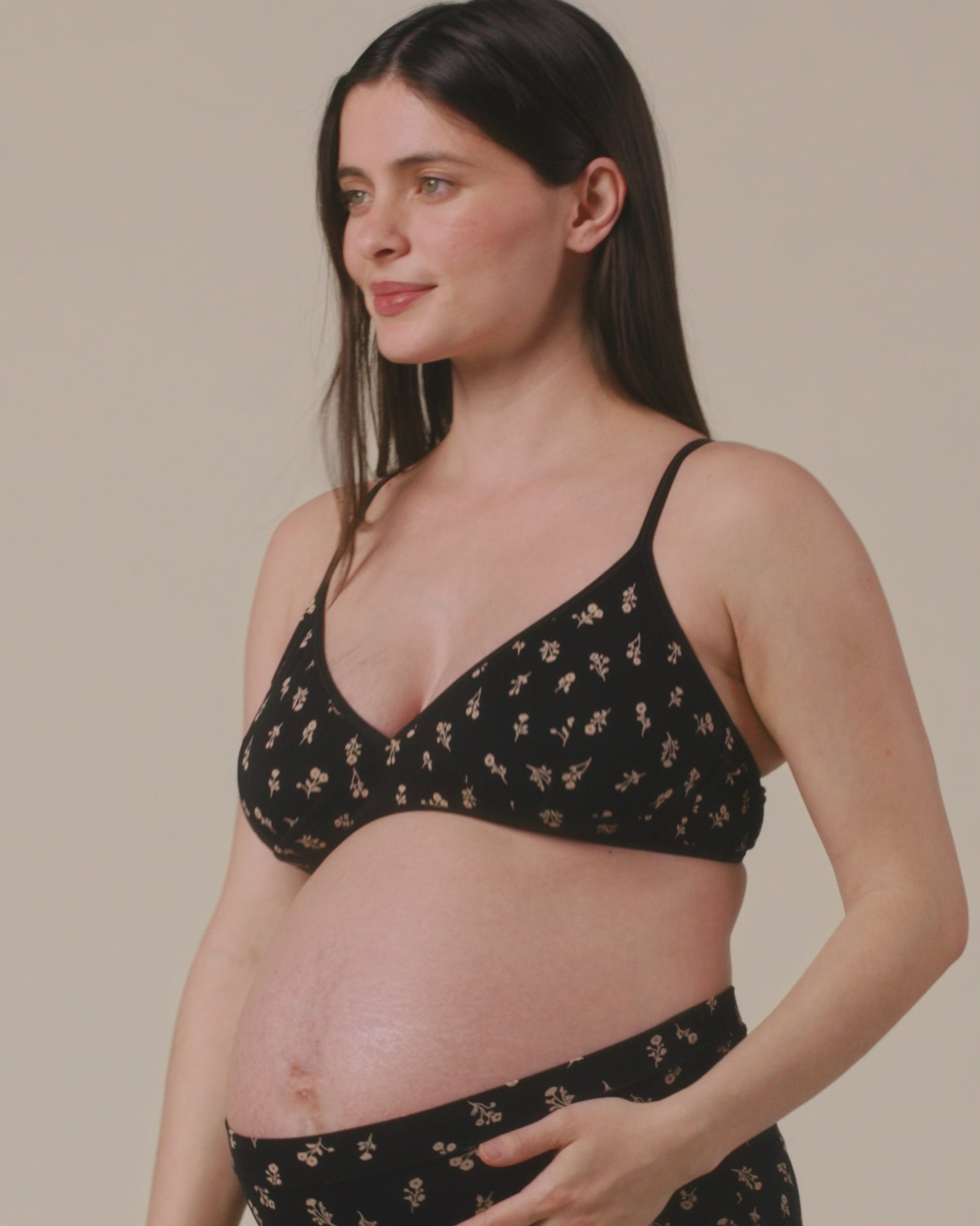 Video of model showing the fit on Every Stage Triangle Bralette in Black Wildflower and Every Stage Brief in Black Wildflower on a beige background