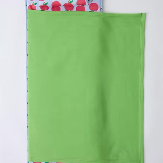 Stop motion video of the Cool Kid Nap Mat in Blue Apple folding up into an easy to carry pack, on a beige background.