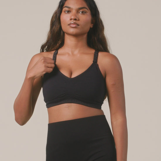 Video of model displaying comfort and function of the Sublime Hands-Free Pumping & Nursing Sports Bra in Black on a beige background. 