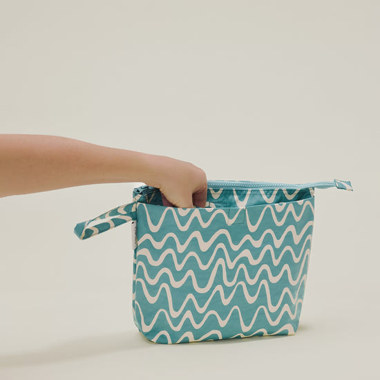 Stop motion video showing a hand putting in and out the changing pad included in the Quick Change Kit Bag in Waves