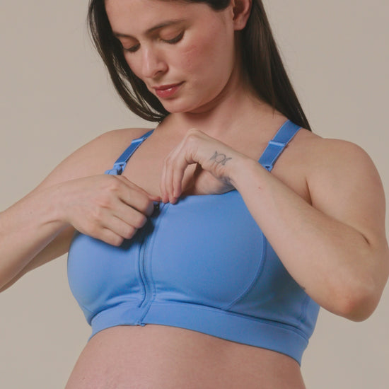 Model showing the supportive features of the High Impact Nursing Sports Bra in Harbor Blue on a beige background