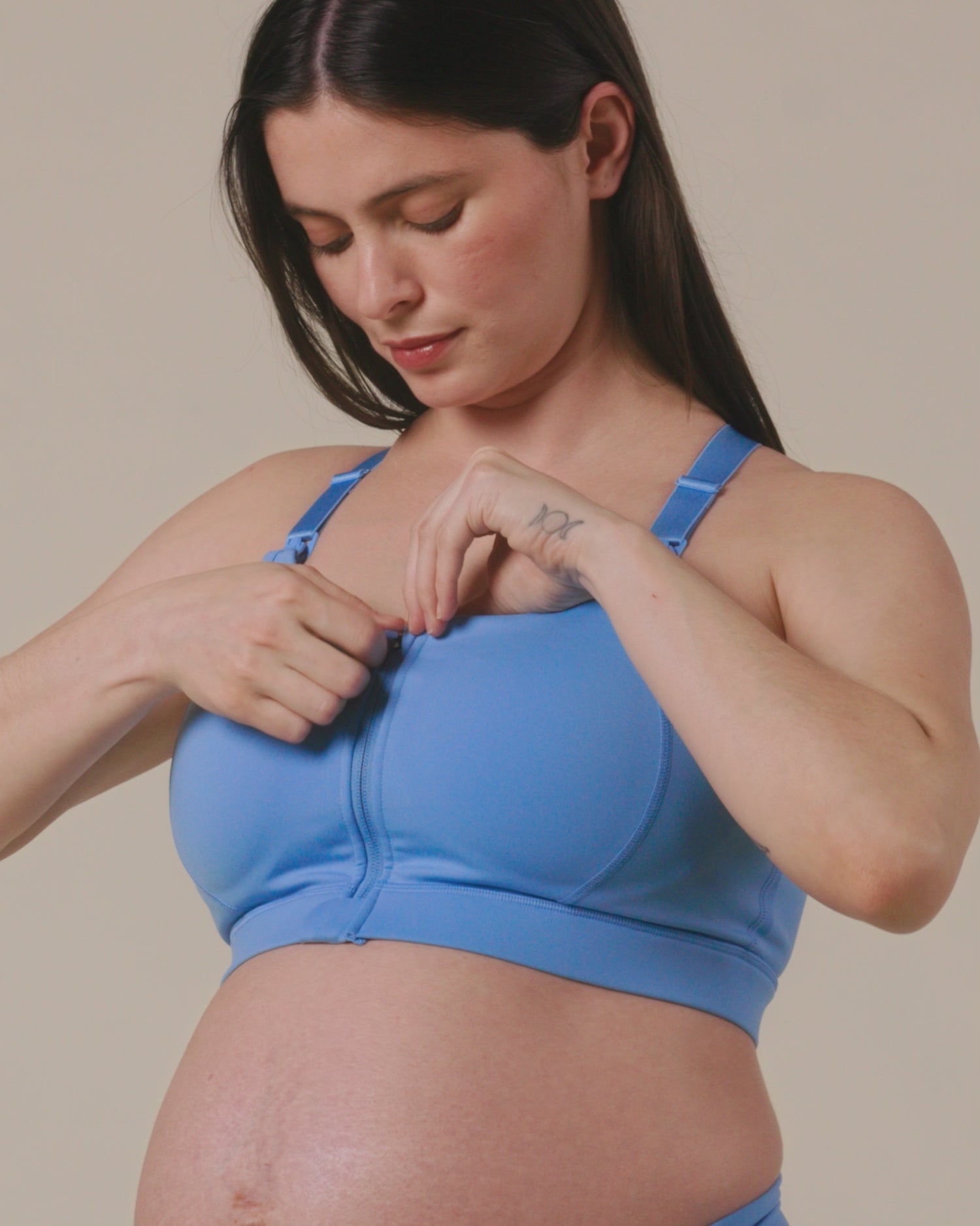 Model showing the supportive features of the High Impact Nursing Sports Bra in Harbor Blue on a beige background