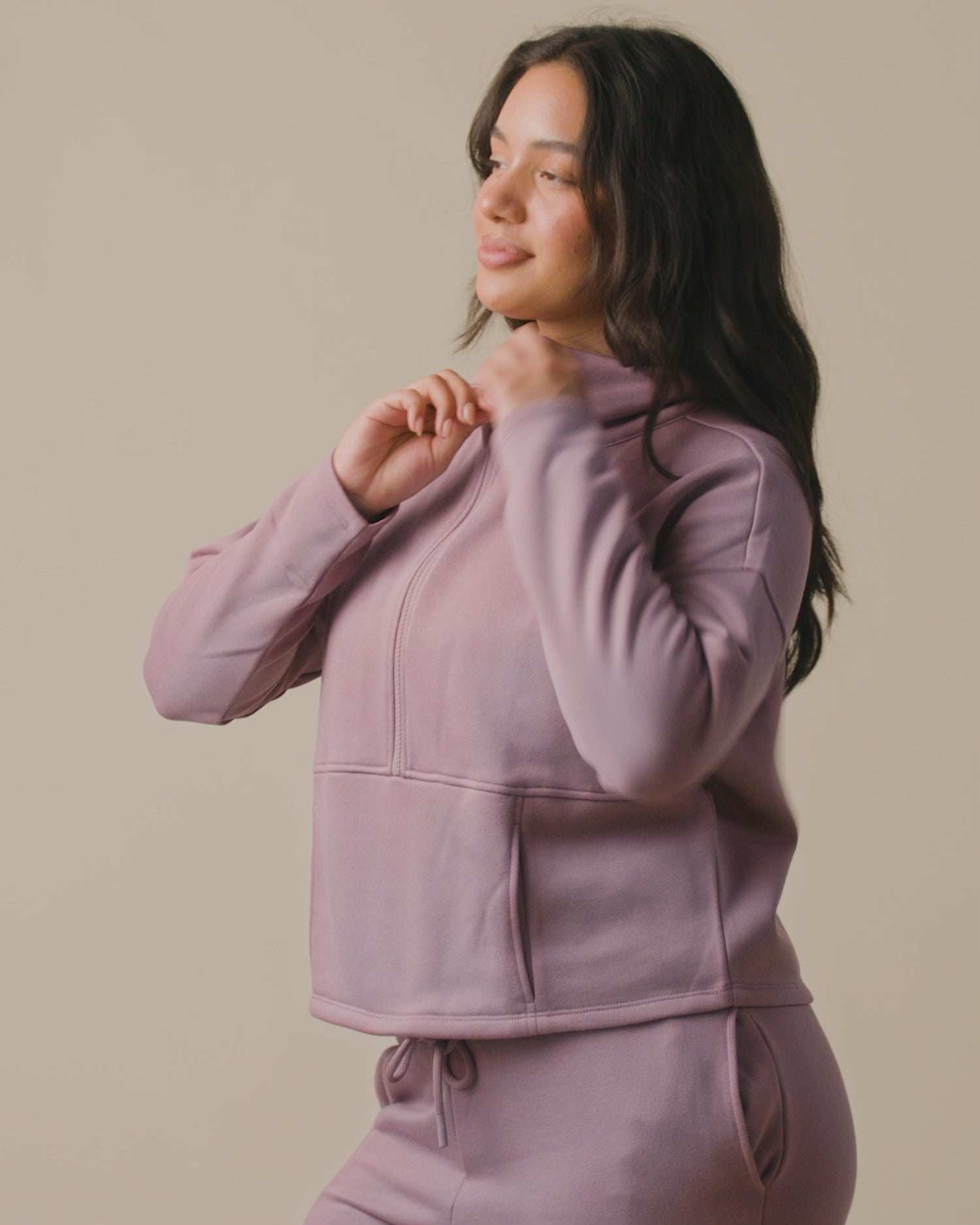 Video of model wearing Cloud Fleece Half Zip Nursing Pullover on a neutral background, showing the front pockets and how the zip opens