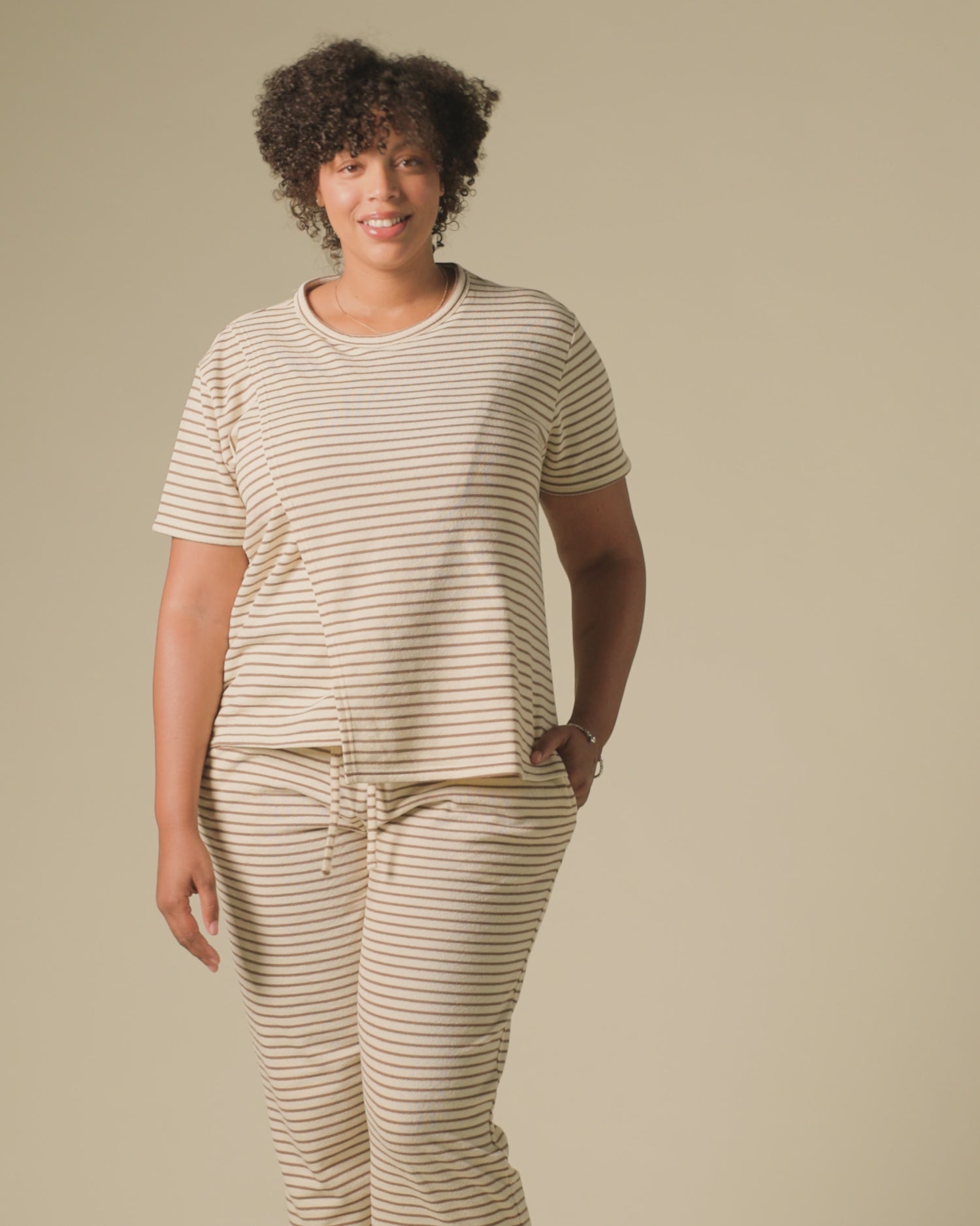 Video of model wearing Luxe Terry Maternity & Nursing Split Hem T-shirt in Ivory & Chocolate Stripe and Luxe Terry Maternity & Postpartum Pant in Ivory & Chocolate Stripe, on a beige background.