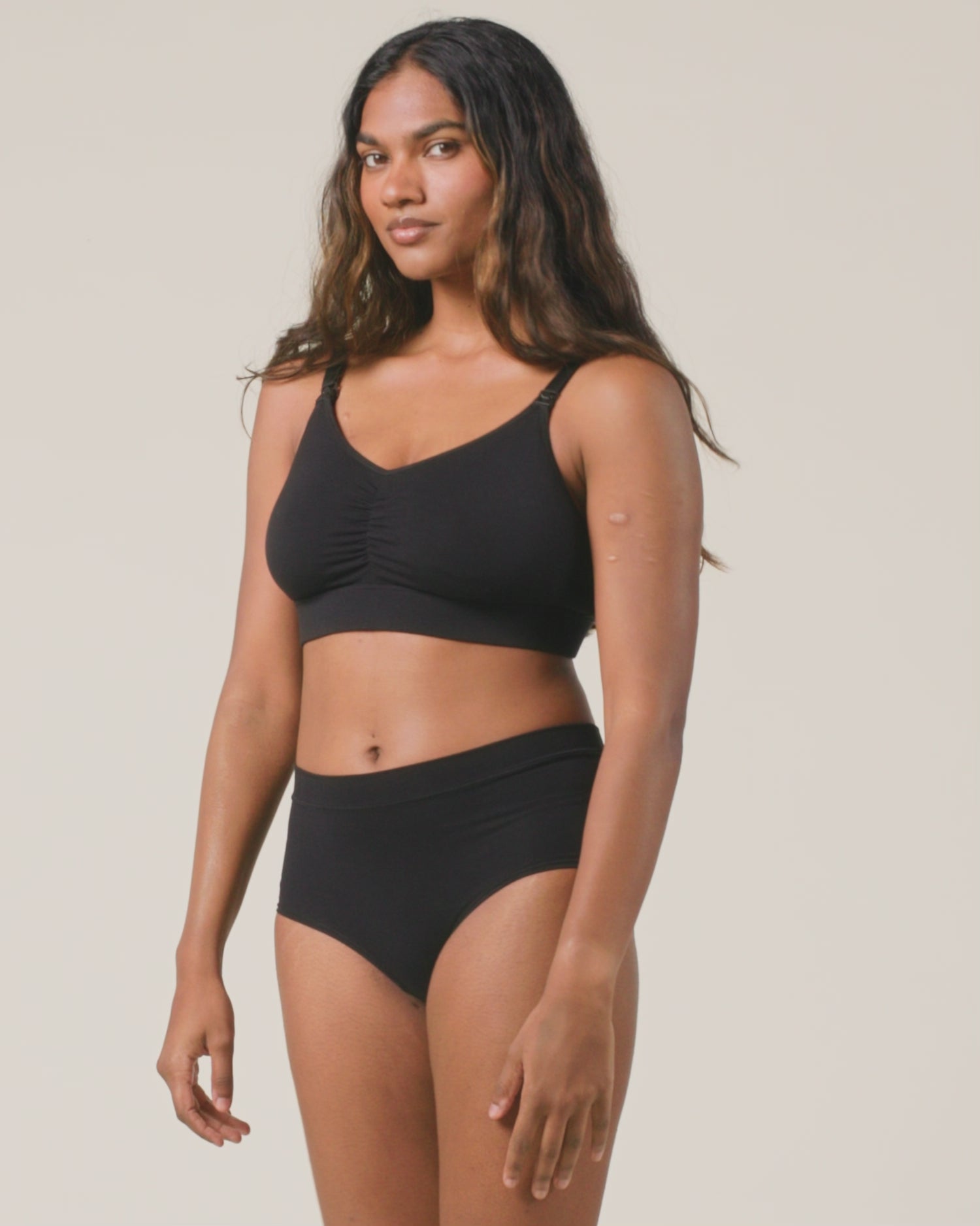Video of model is showing the fit on Every Stage Nursing Bra and Every Stage Brief in Black on a beige background 
