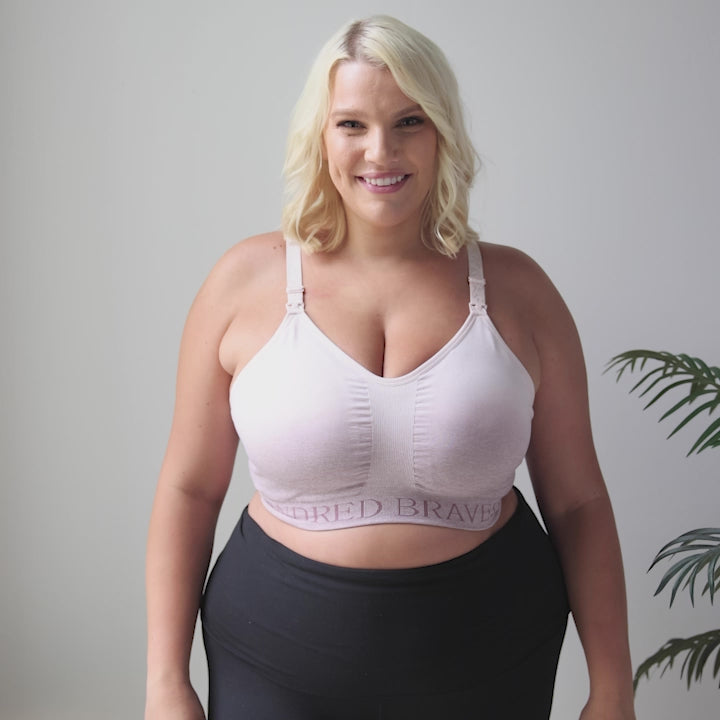 Video showing a model wearing the Sublime® Hands-Free Pumping & Nursing Sports Bra in Ombre Purple, showing the easy clip down nursing access on the bra, demonstrating the comfortable fit and the underwire free design. She also shows off the comfortable straps on the back of the sports bra and the breathable fabric.