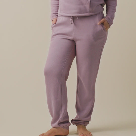 Video of model wearing Cloud Fleece Jogger on a neutral background, showing the strings for tying at the front and the side pockets
