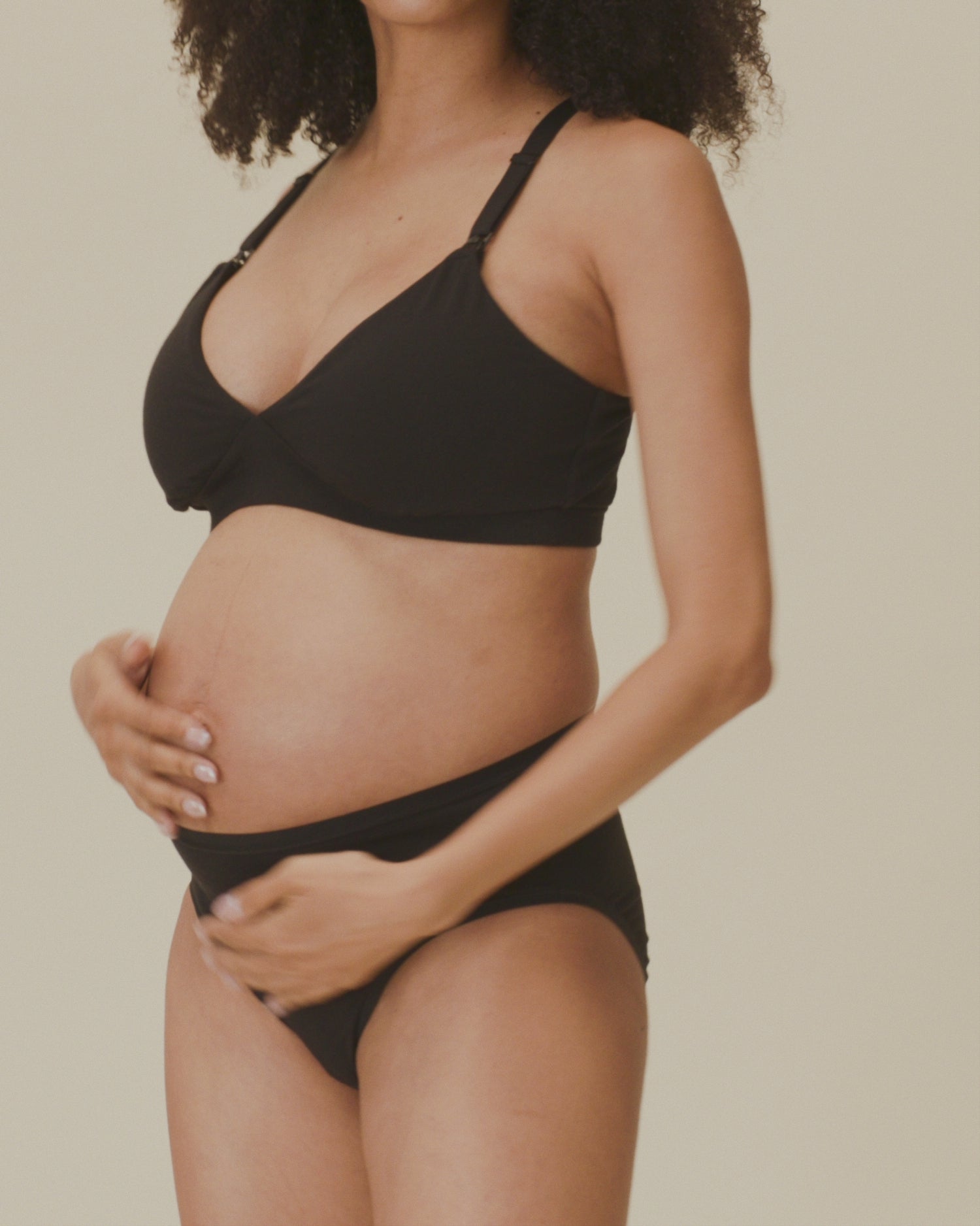 Video of model showing the soft fit of the SoftStretch Cotton Maternity & Nursing Bralette in Black and SoftStretch Cotton Maternity & Postpartum Brief in Black on a beige background.