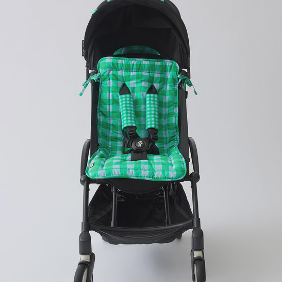 Video of black stroller with Stroller Party™ Seat Liner & Strap Covers, Clips, and Caddy Bag in Teal Gingham on a beige background.