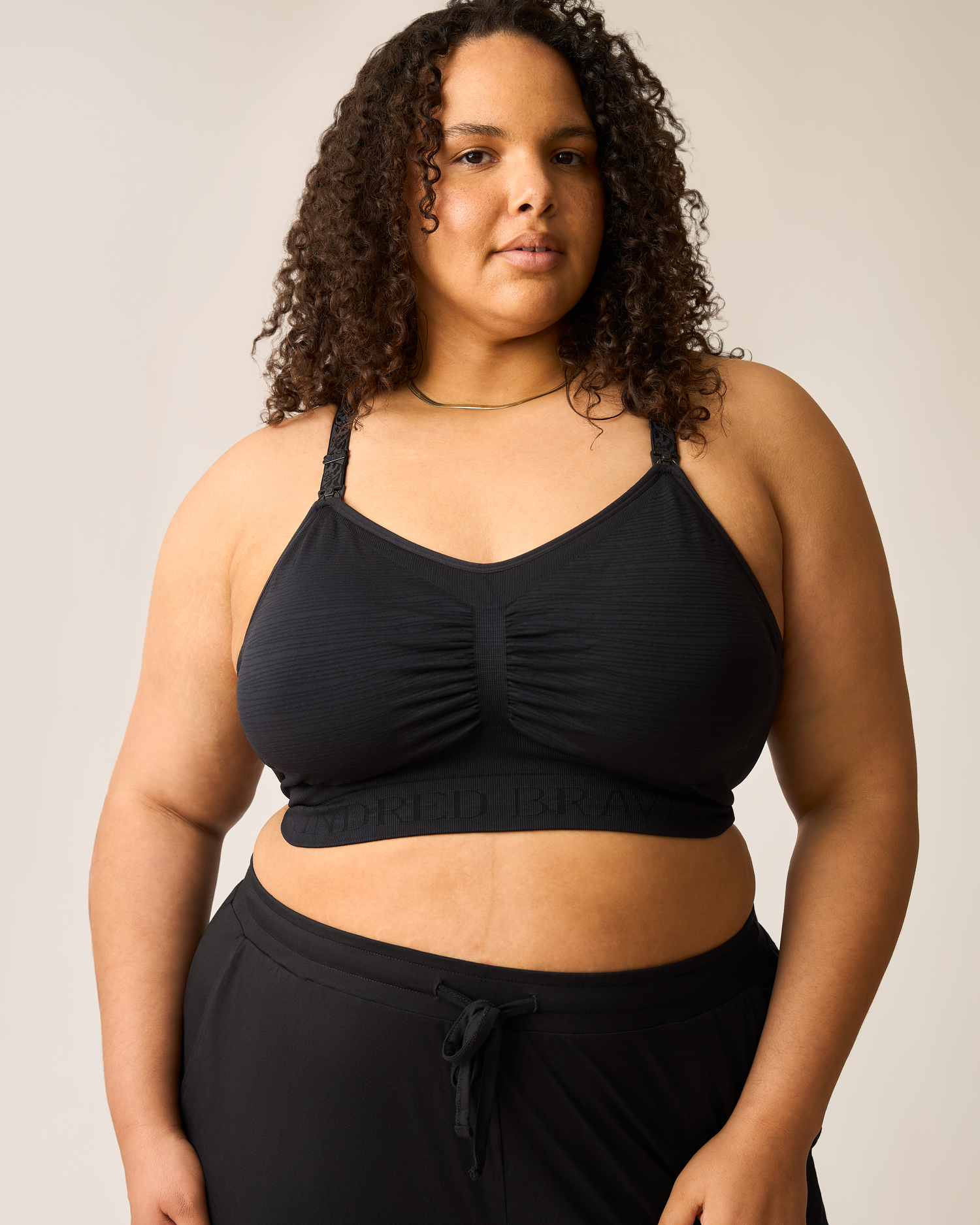 Woman wearing the Sublime® Hands-Free Pumping & Nursing Bra in black on plain background